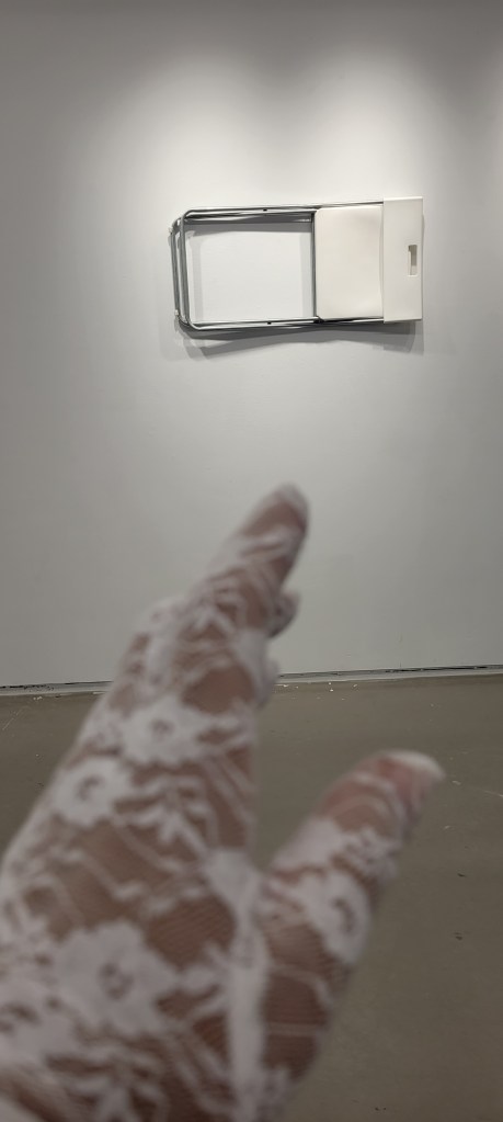 Hand wearing lace glove pointing to white folding chair